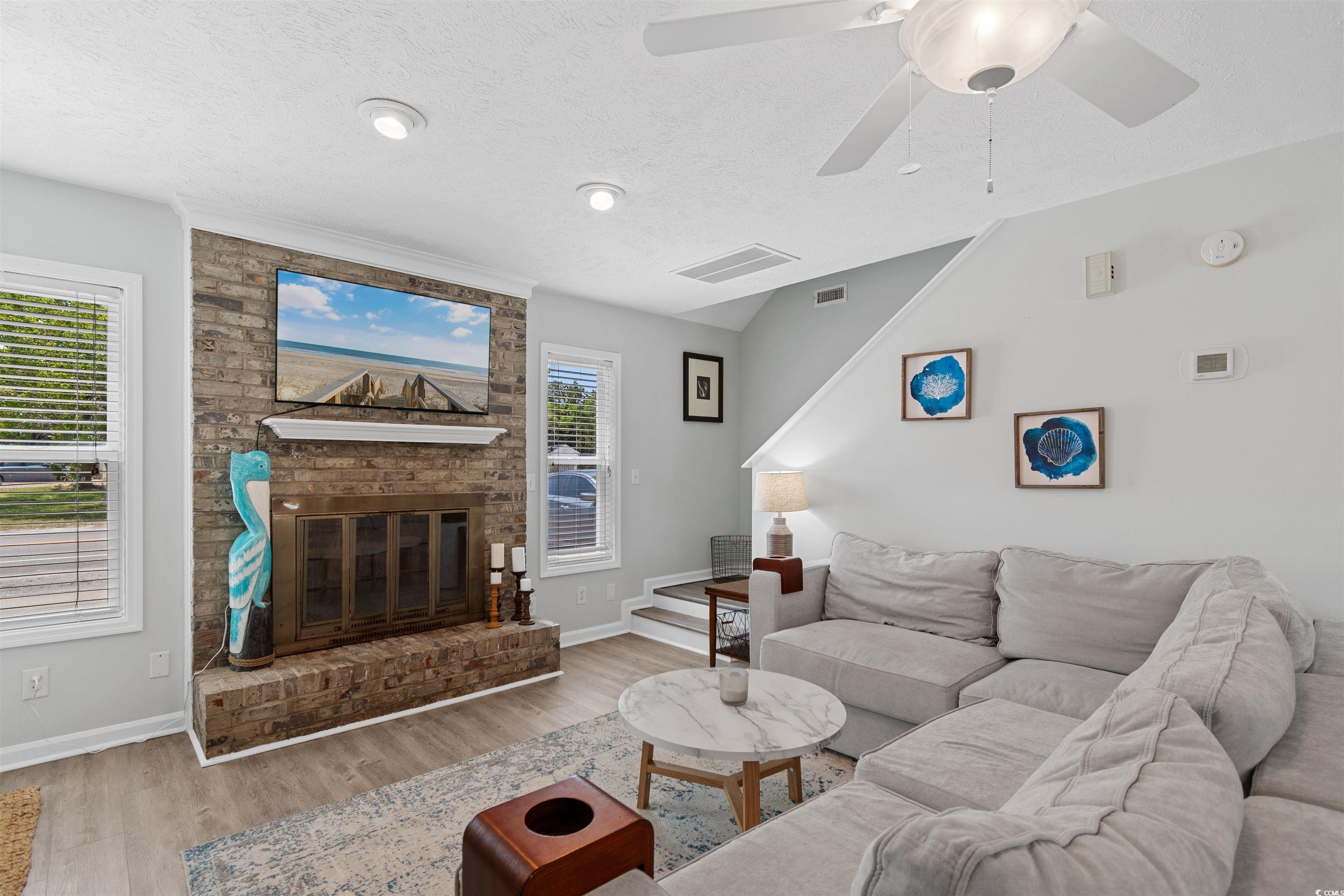 605 A 17th Avenue South North Myrtle Beach, SC 29582 - Photo 12 of 36 Living room with stairway, wood finished floors, a textured ceiling, a brick fireplace, and a ceiling fan