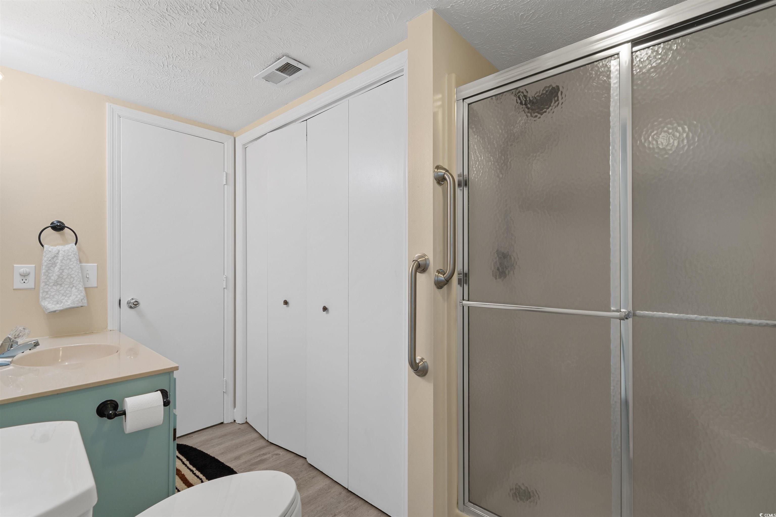 605 A 17th Avenue South North Myrtle Beach, SC 29582 - Photo 19 of 36 Bathroom featuring a textured ceiling, a shower stall, vanity, light wood-type flooring, and a closet