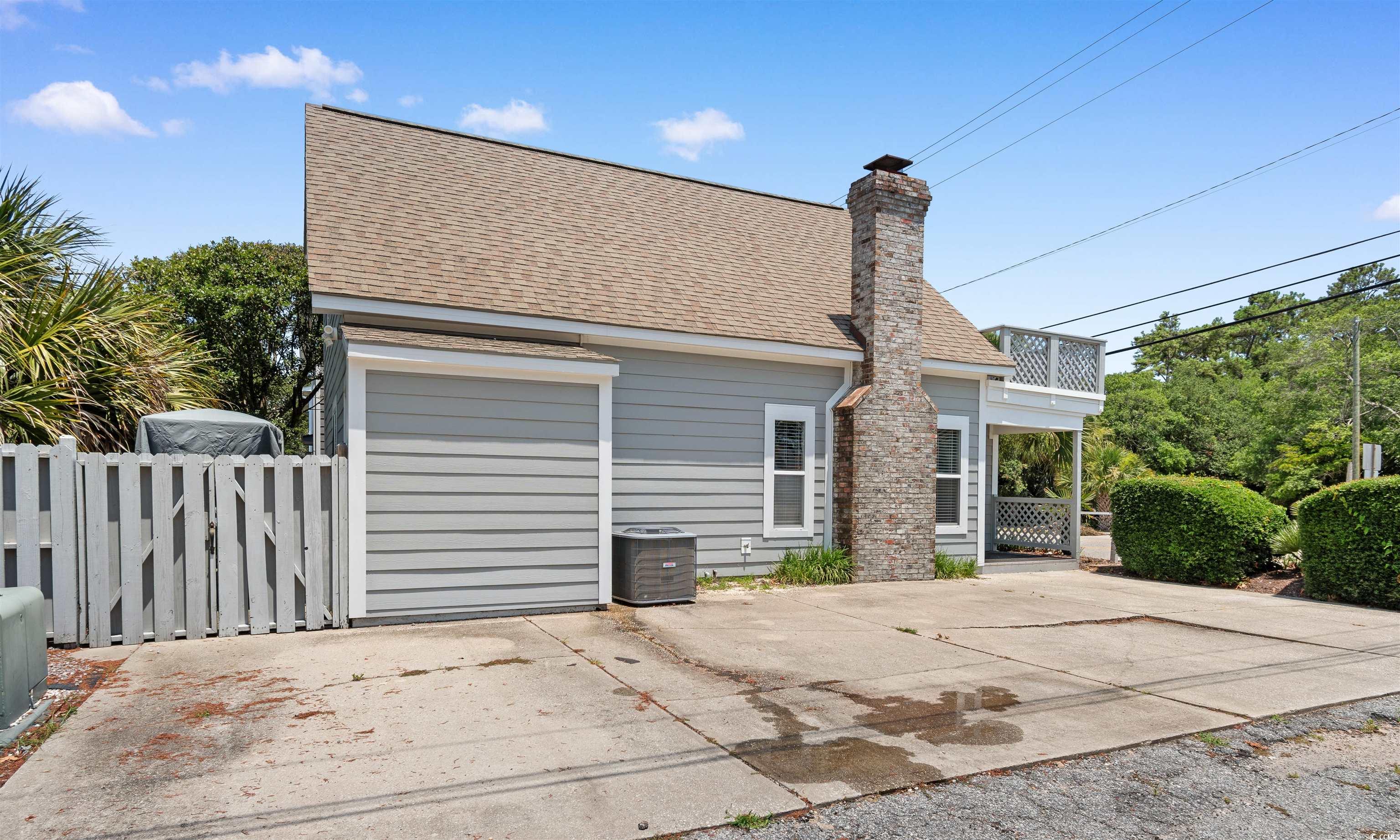 605 A 17th Avenue South North Myrtle Beach, SC 29582 - Photo 35 of 36 Back of property featuring roof with shingles, a chimney, a balcony, and driveway