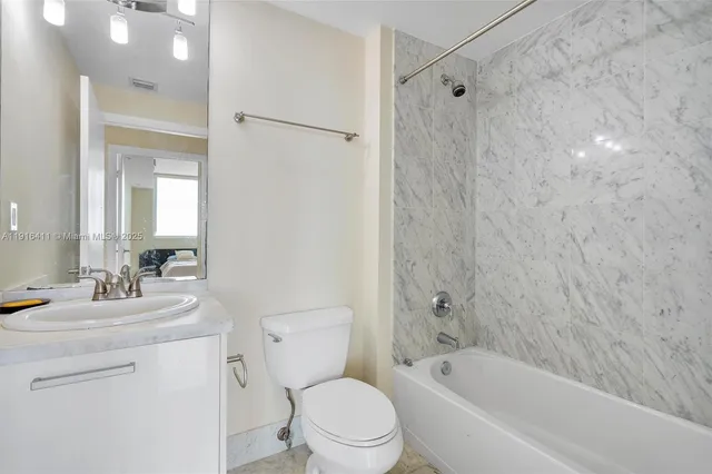 a bathroom with a bathtub shower sink vanity mirror and toilet