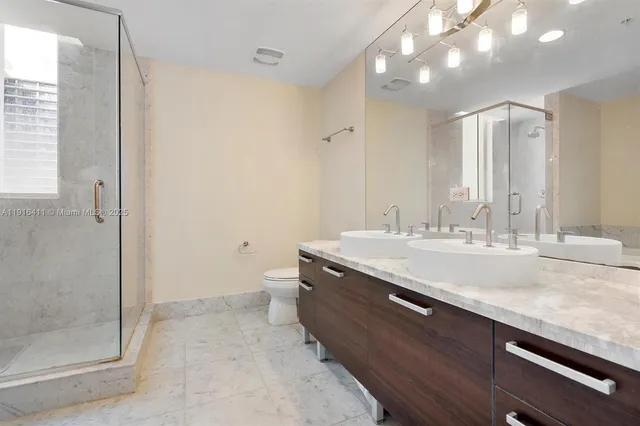 a bathroom with a granite countertop sink a toilet and shower