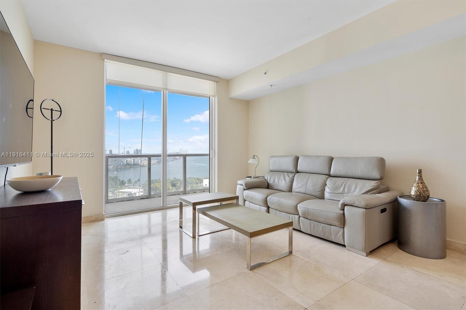 253 Northeast 2nd Street, Unit 1803 Miami, FL 33132 - Photo 2 of 23 a living room with furniture and a floor to ceiling window
