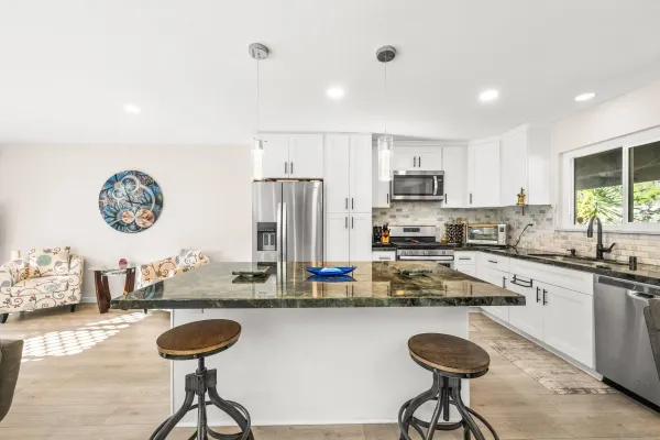 a kitchen with stainless steel appliances granite countertop a sink a stove a refrigerator cabinets and chairs