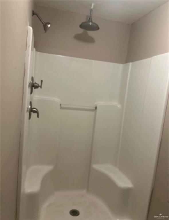 4621 North Jackson Road Edinburg, TX 78541 - Photo 6 of 7 White shower enclosure featuring dual shower heads, integrated seating, and a grab bar
