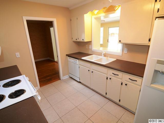 1314 Erinshire Road Charlotte, NC 28211 - Photo 4 of 16 a kitchen with granite countertop white cabinets and black appliances