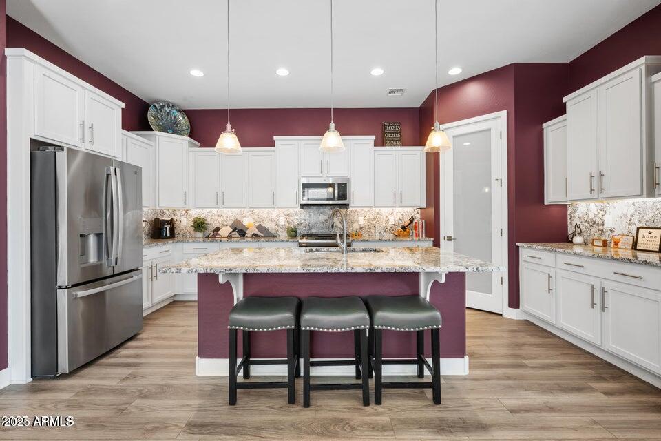 18427 West Clinton Street Surprise, AZ 85388 - Photo 4 of 6 a kitchen with granite countertop a table chairs stainless steel appliances and cabinets