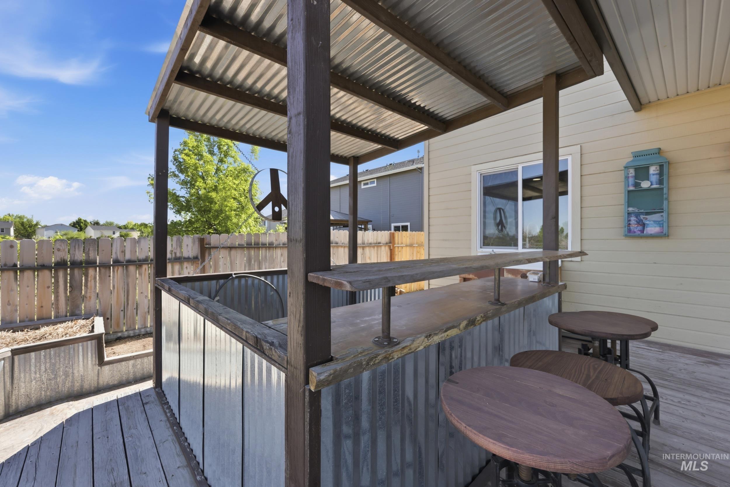 4855 South Chex Way Boise, ID 83709 - Photo 29 of 47 Outdoor bar structure with corrugated metal siding and roof, featuring a wooden countertop and a wood-finish deck