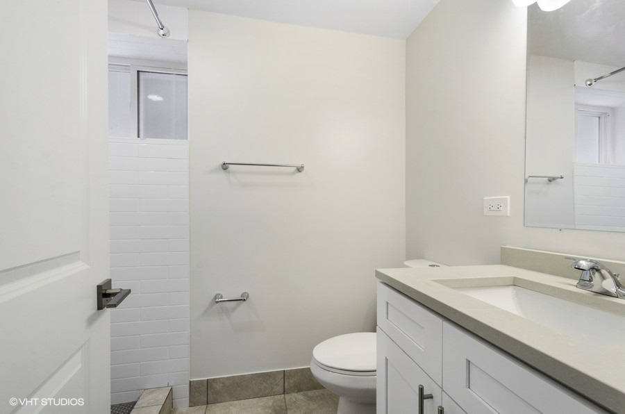 5816 North Ridge Avenue, Unit 1F Chicago, IL 60660 - Photo 15 of 18 a bathroom with a granite countertop sink a toilet and a mirror