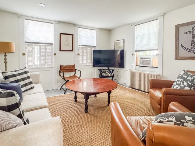 a living room with furniture a flat screen tv and a window