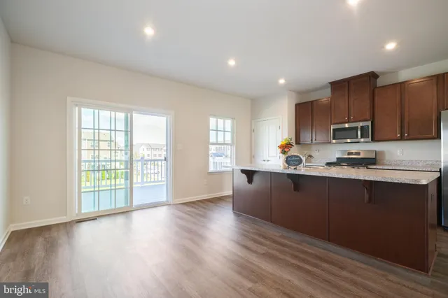 a kitchen with stainless steel appliances granite countertop a stove a sink a refrigerator with wooden cabinets and a window