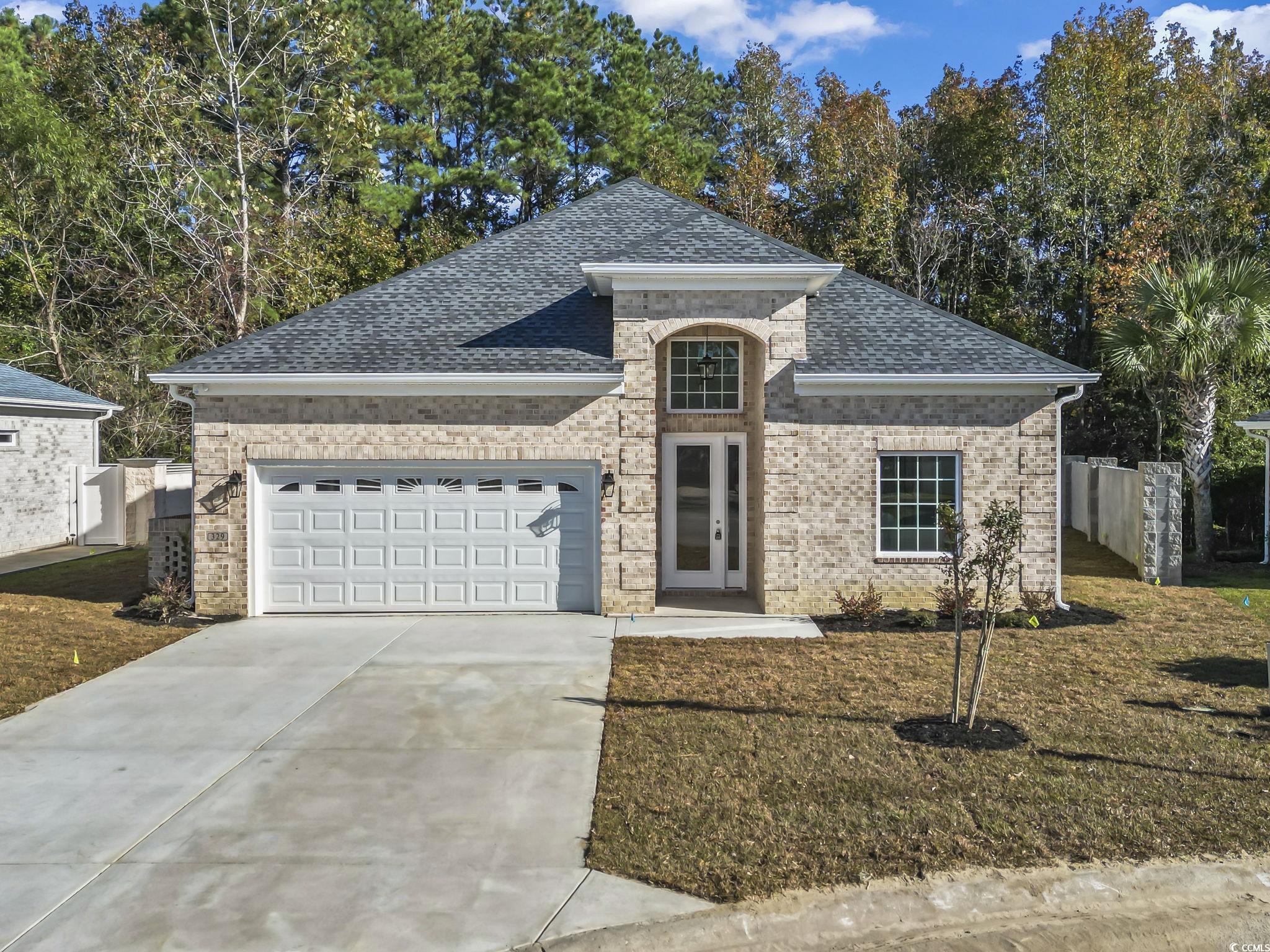 French provincial home featuring a shingled roof, brick siding, driveway, and an attached garage