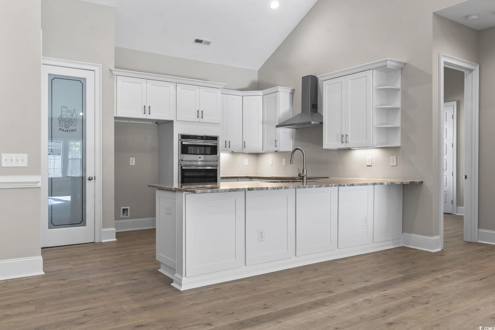 329 Waterfall Circle Little River, SC 29566 - Photo 13 of 39 Kitchen with open shelves, white cabinets, wall chimney range hood, dark stone counters, and a peninsula