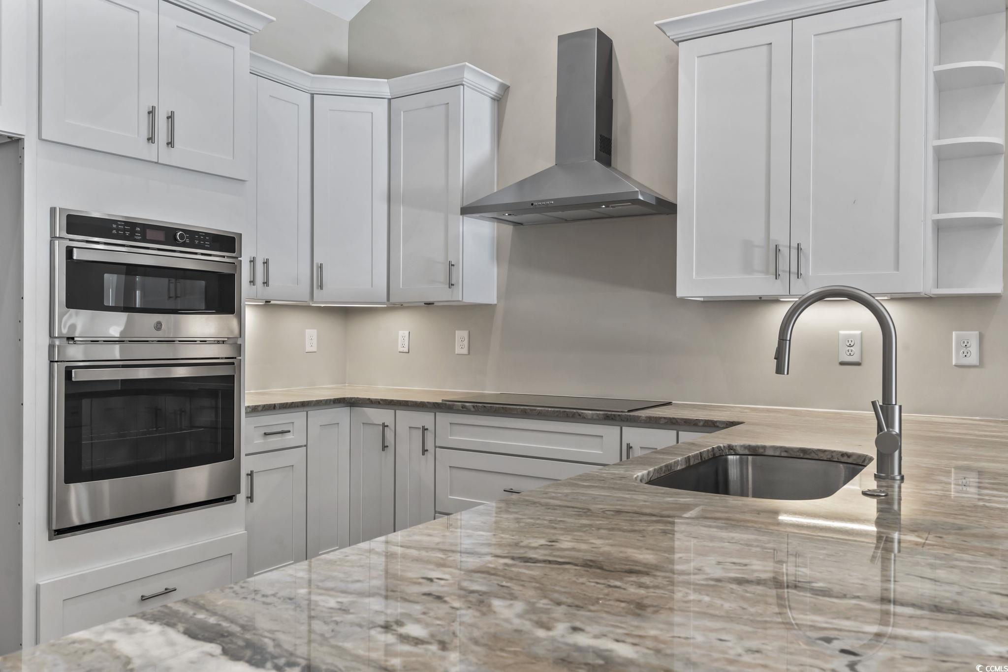 329 Waterfall Circle Little River, SC 29566 - Photo 15 of 39 Kitchen featuring open shelves, wall chimney exhaust hood, double oven, light stone counters, and white cabinetry
