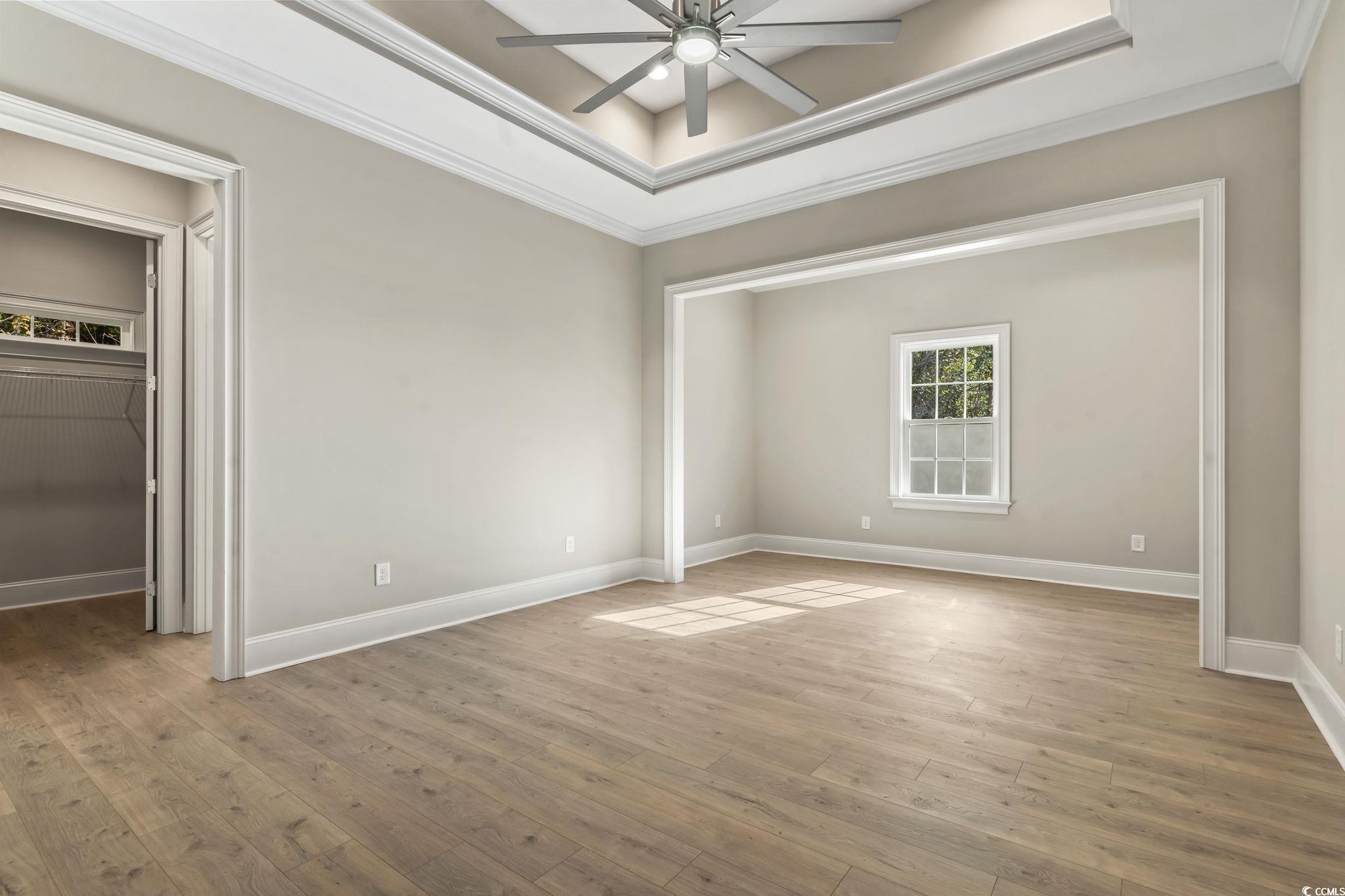 329 Waterfall Circle Little River, SC 29566 - Photo 25 of 39 Unfurnished bedroom with a tray ceiling, crown molding, light wood-style floors, a ceiling fan, and a spacious closet
