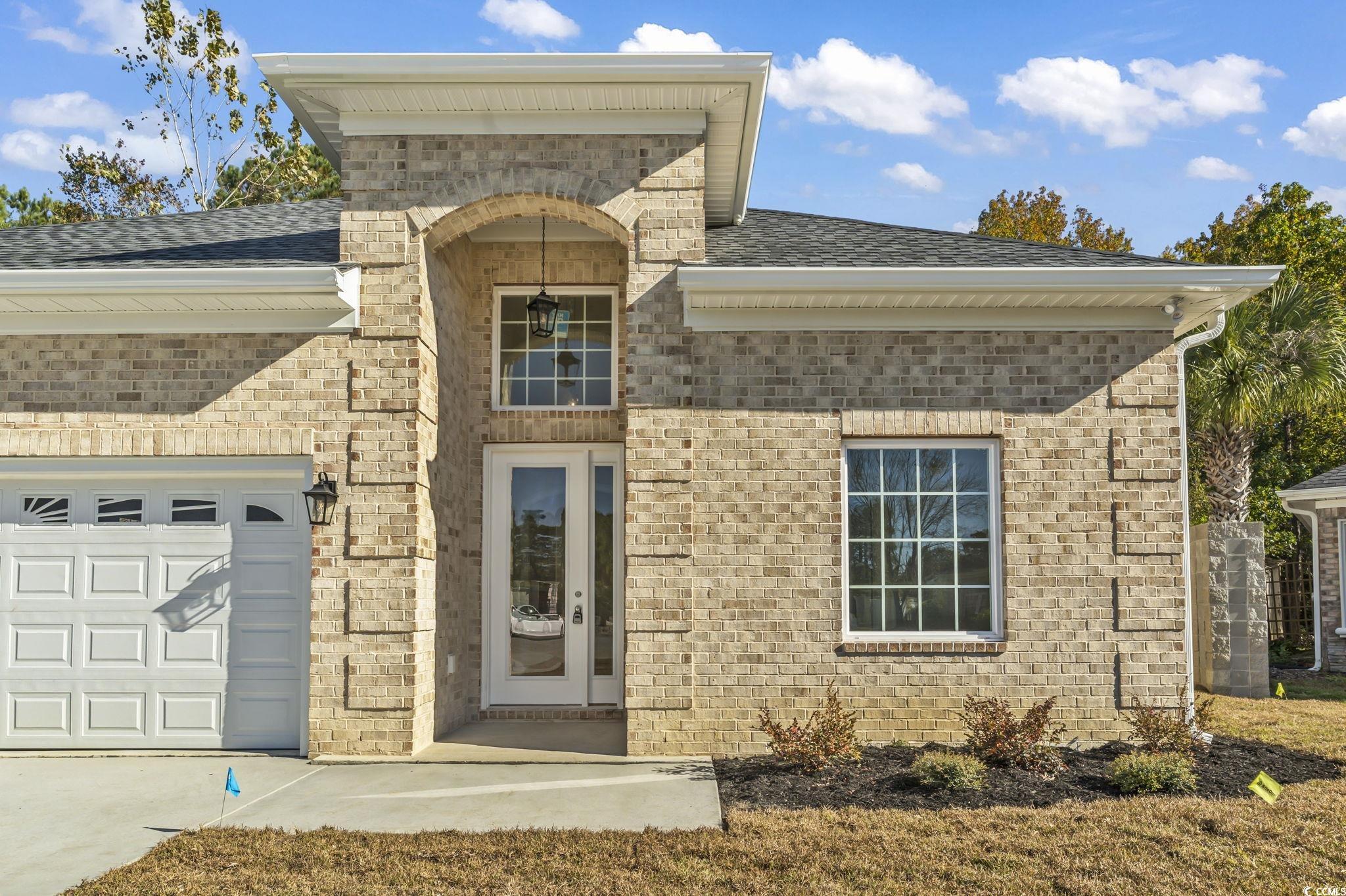 329 Waterfall Circle Little River, SC 29566 - Photo 4 of 39 Property entrance featuring a garage, roof with shingles, brick siding, and concrete driveway