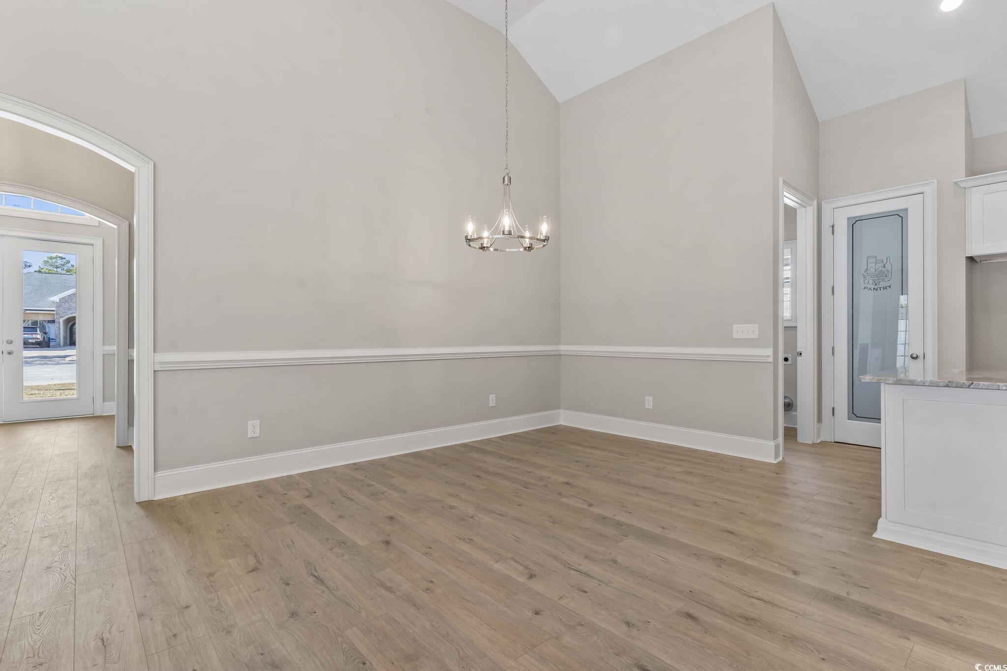 329 Waterfall Circle Little River, SC 29566 - Photo 10 of 39 Unfurnished dining area with light wood finished floors, a chandelier, and high vaulted ceiling