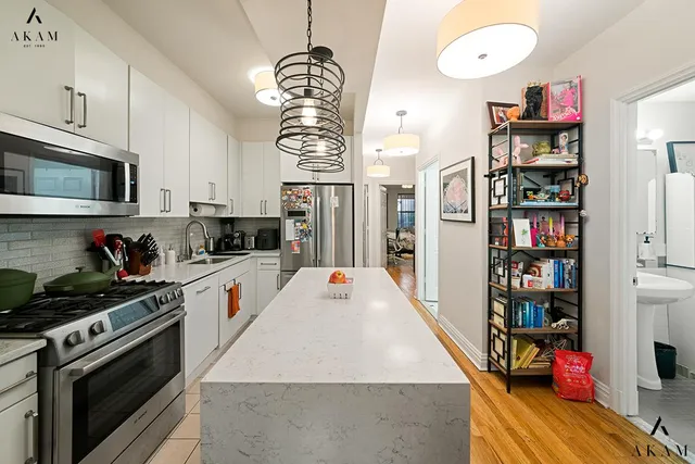 a kitchen with stainless steel appliances granite countertop a stove refrigerator and a wooden floor