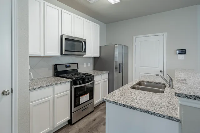 a kitchen with granite countertop a sink stove and refrigerator