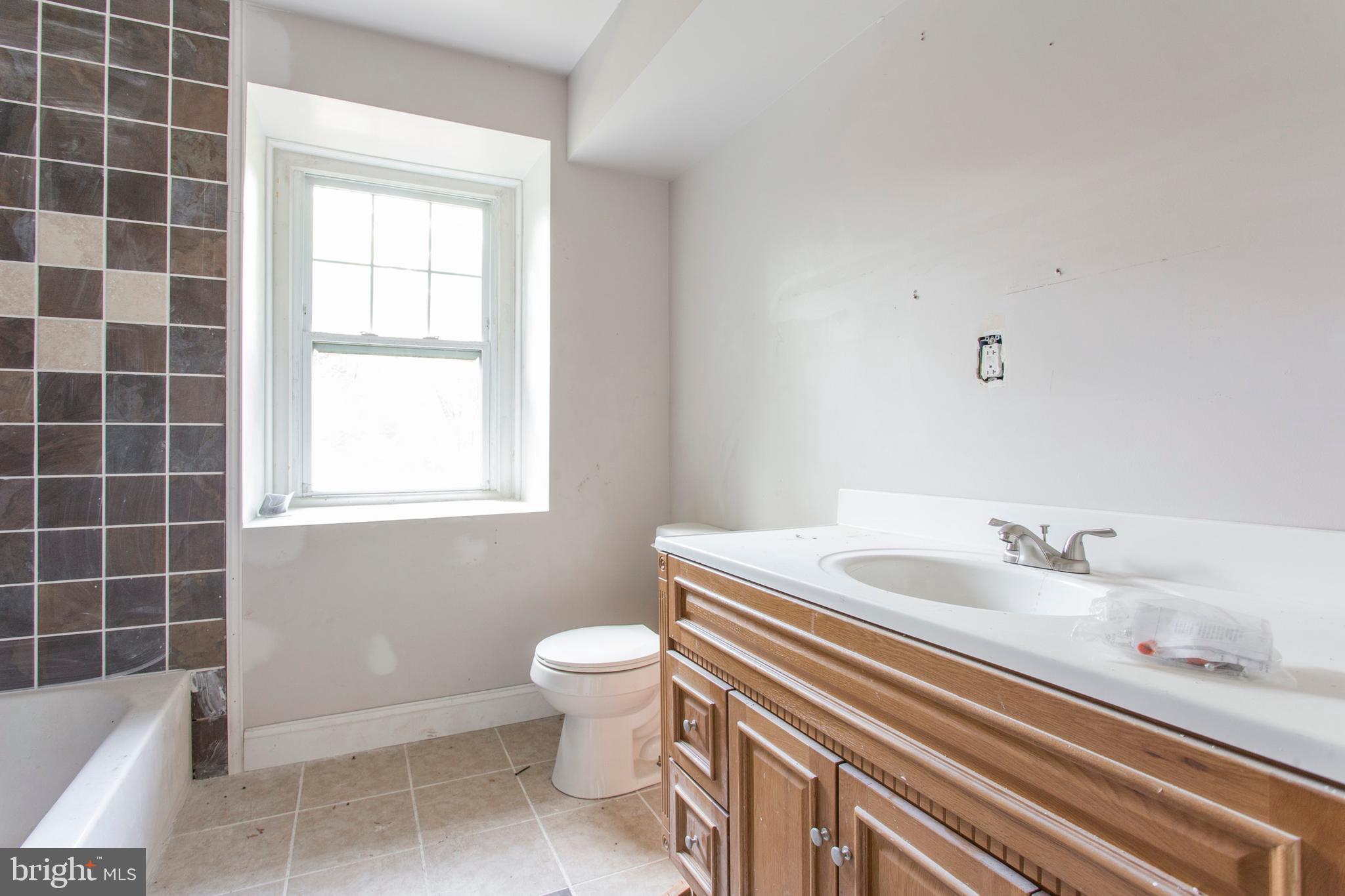 5200 Overbrook Avenue Philadelphia, PA 19131 - Photo 24 of 37 a bathroom with a granite countertop sink a toilet and a mirror