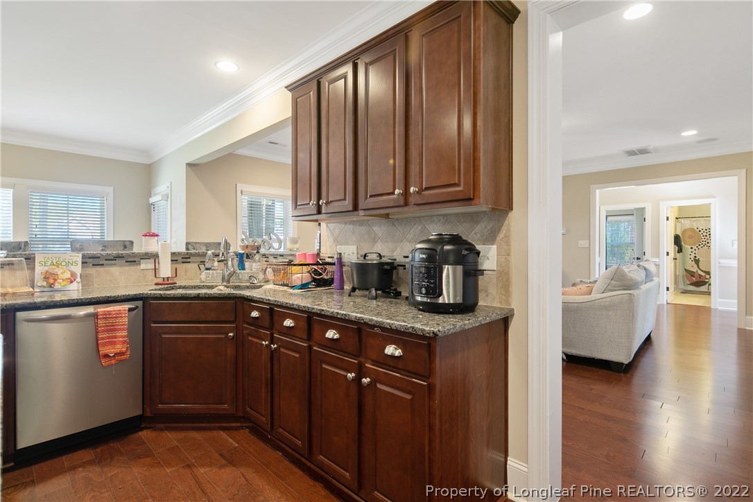 180 The Inner Circle Spring Lake, NC 28390 - Photo 17 of 50 a kitchen with stainless steel appliances granite countertop wooden cabinets a sink and dishwasher