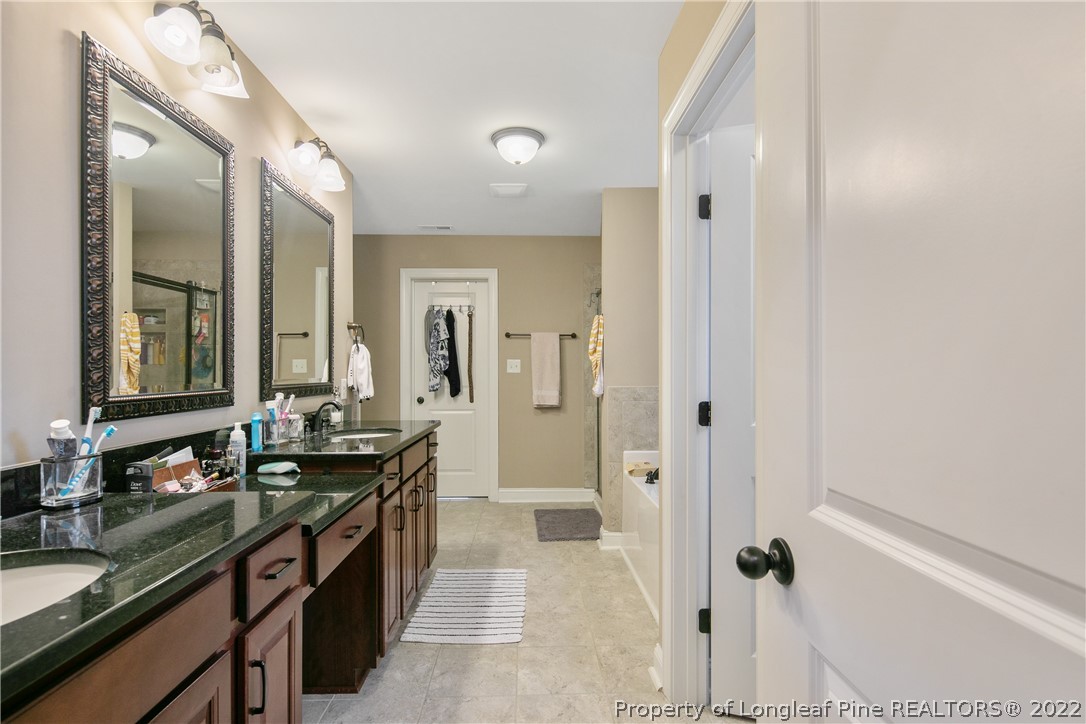 180 The Inner Circle Spring Lake, NC 28390 - Photo 30 of 50 a spacious bathroom with a granite countertop sink a toilet a mirror and shower