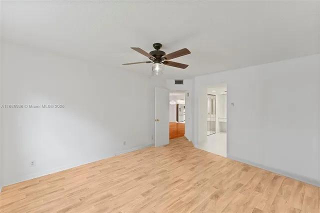 a view of empty room with wooden floor and ceiling fan