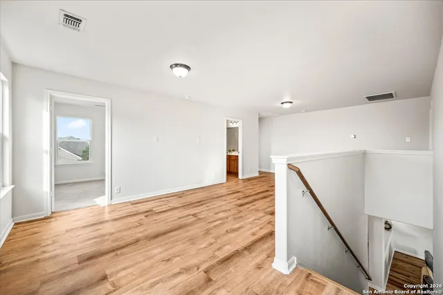 a view of an empty room with wooden floor and a bathroom