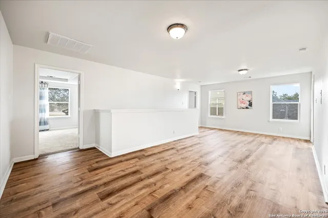 a view of empty room with wooden floor and fan