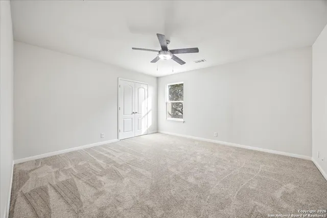 en empty room with windows and ceiling fan