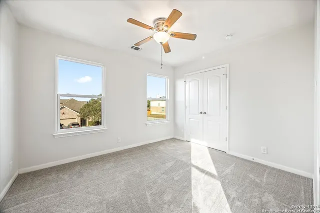 an empty room with windows and fan