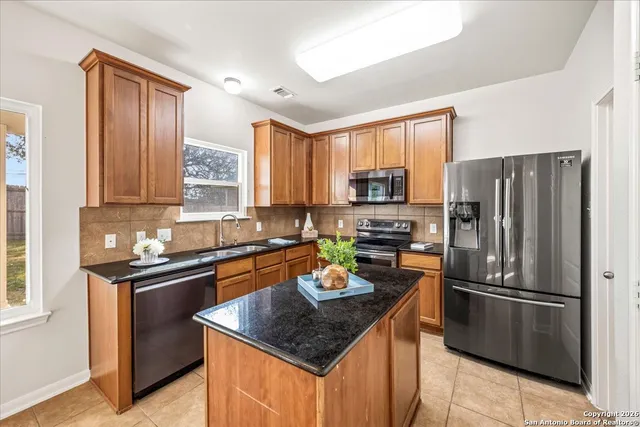 a kitchen with stainless steel appliances granite countertop a refrigerator a sink a stove a microwave and island