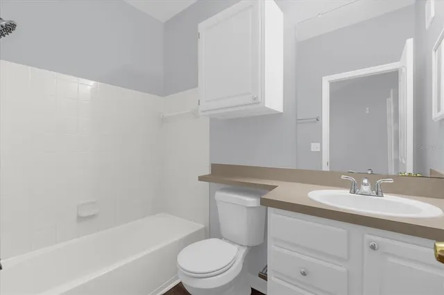 a bathroom with a granite countertop toilet a sink a mirror and bathtub