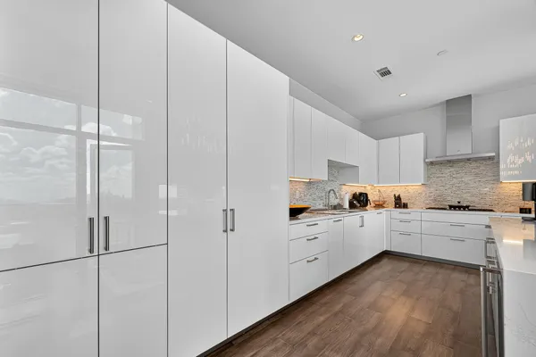 a kitchen with white cabinets a sink dishwasher and a stove with wooden floor