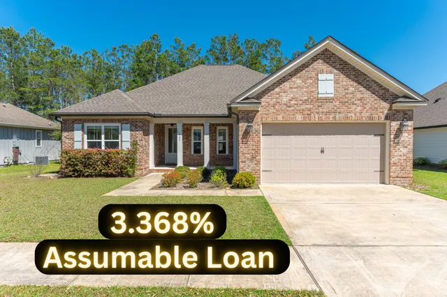 a view of a house with a yard plants and large tree