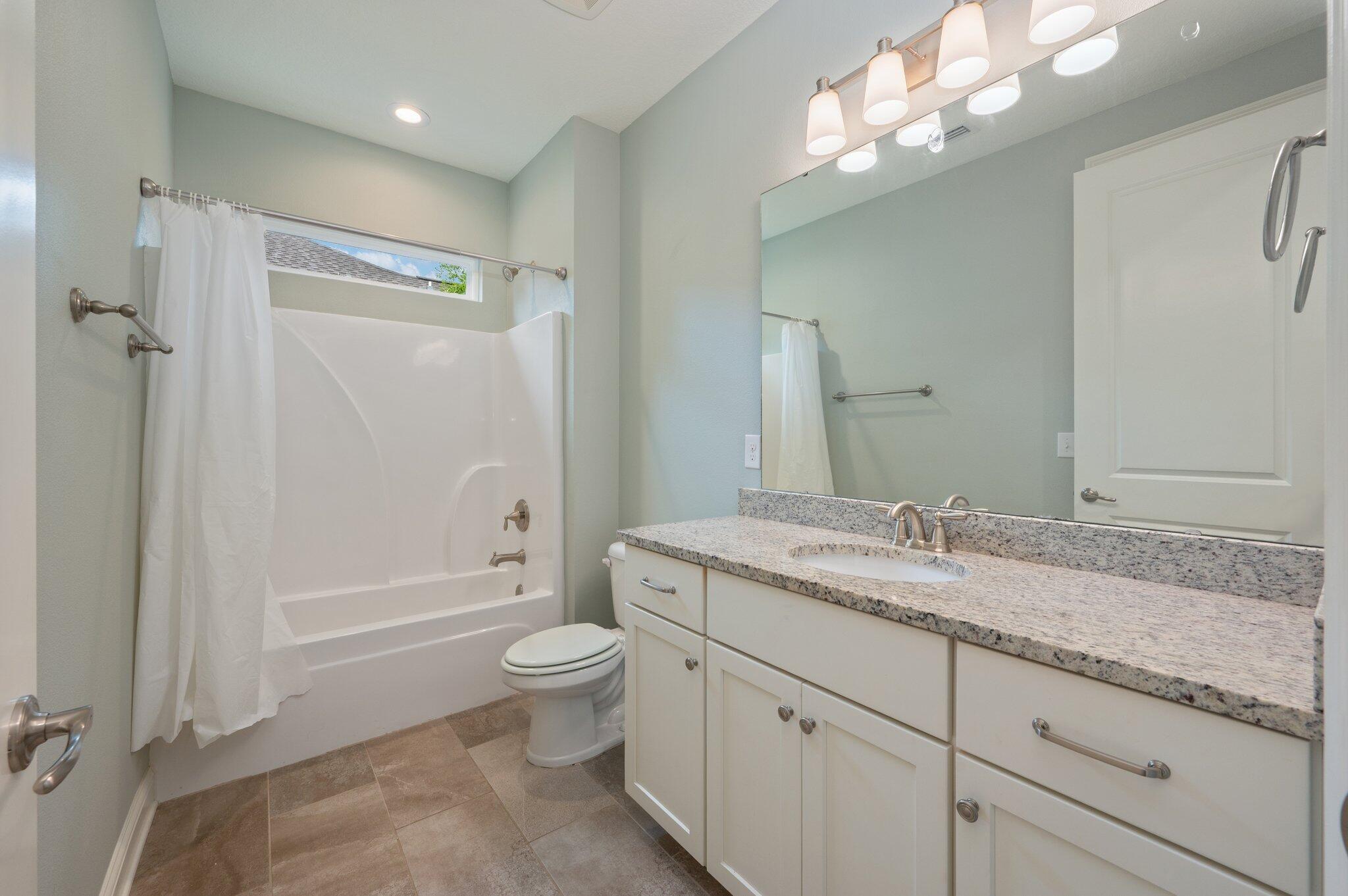 125 Perimeter Place Freeport, FL 32439 - Photo 19 of 26 a bathroom with a granite countertop sink toilet a large mirror a shower and a bathtub