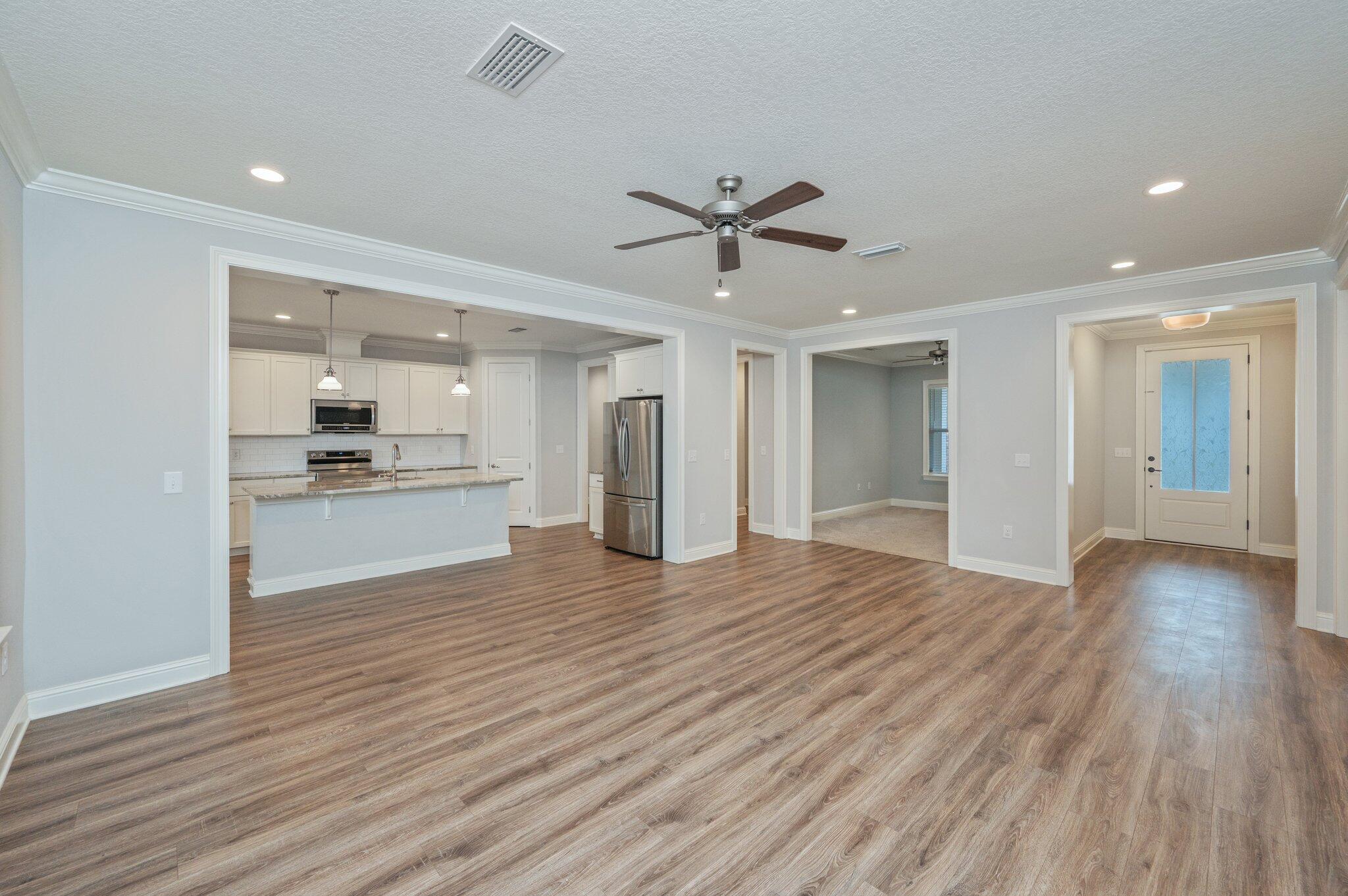 125 Perimeter Place Freeport, FL 32439 - Photo 3 of 26 a view of an empty room and kitchen with wooden floor and a kitchen