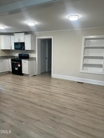 an empty room with chandelier fan and windows