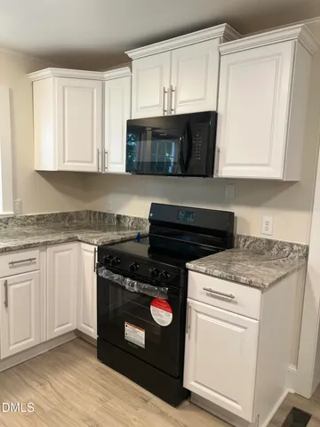 a kitchen with granite countertop a refrigerator and a stove top oven