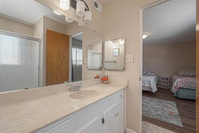 a en suite bathroom with a granite countertop sink a toilet and a mirror