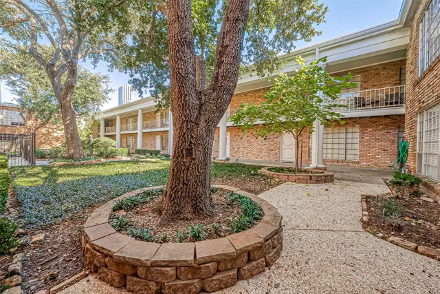 a view of a house with a yard fire pit and a large tree