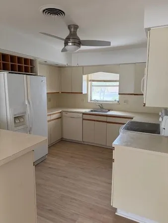 a kitchen with a sink a stove a refrigerator and white cabinets