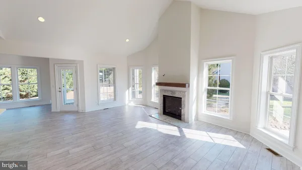 an empty room with wooden floor fireplace and windows