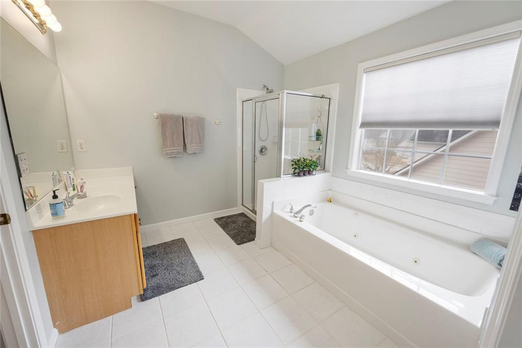 3905 Embassy Way Lilburn, GA 30047 - Photo 12 of 29 a bathroom with a tub a sink and a large mirror next to a window