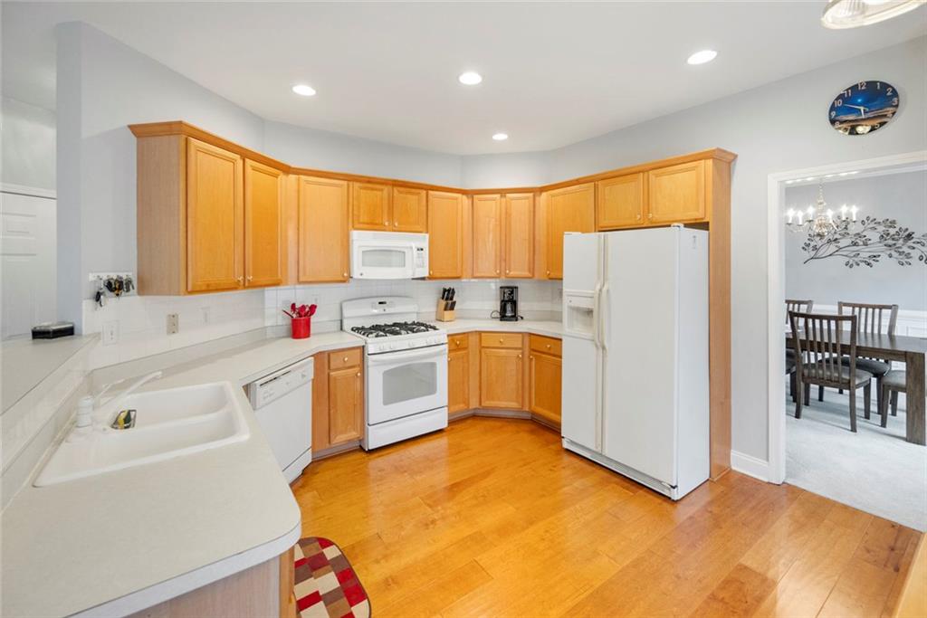 3905 Embassy Way Lilburn, GA 30047 - Photo 7 of 29 a kitchen with a refrigerator a stove a microwave and a dining table with wooden floor