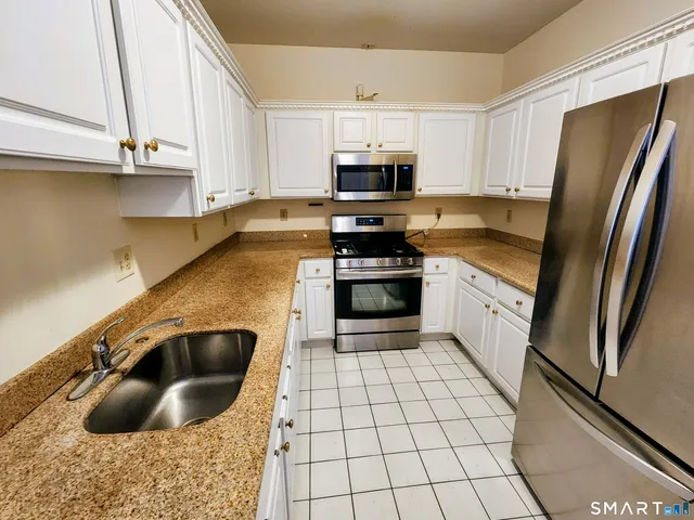 a kitchen with stainless steel appliances granite countertop a sink a stove and a refrigerator