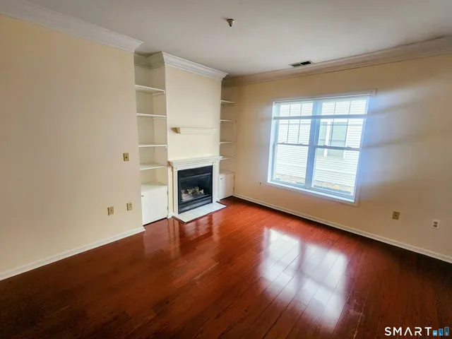 an empty room with wooden floor fireplace and windows