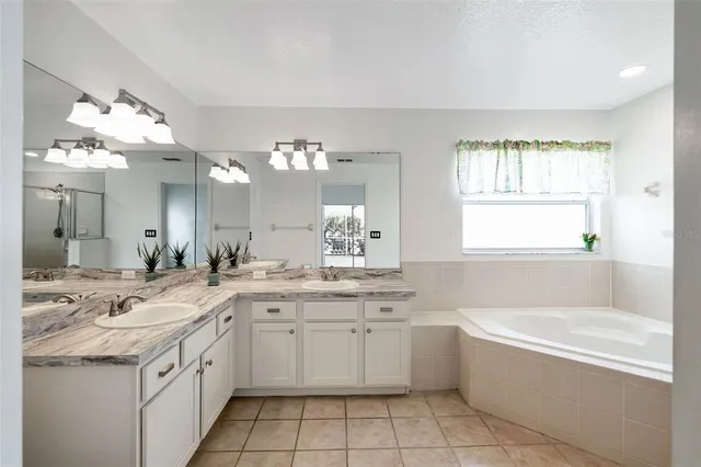 a bathroom with a granite countertop sink a large mirror a bathtub and next to a window