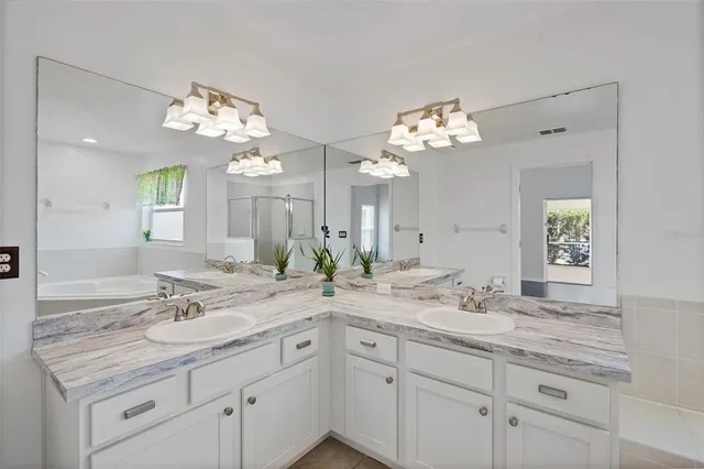 a bathroom with a granite countertop double vanity sink and a mirror