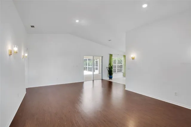 a view of an empty room with wooden floor and windows