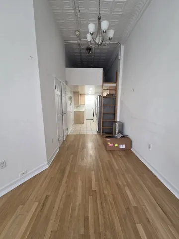 an empty room with wooden floor a chandelier fan and windows